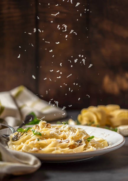 Pasta fettuccine with mushrooms and fried chicken ham in creamy cheese sauce on a light wooden background