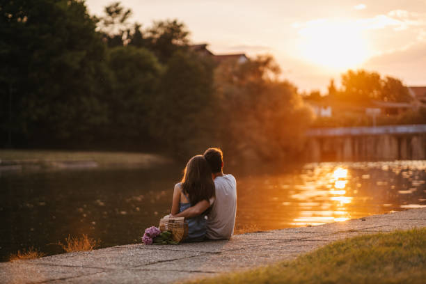istock Couple sitting by the river at sunset 1319212114