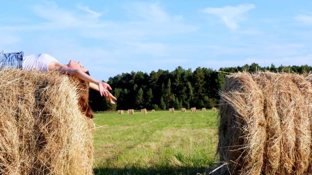 istock young female lies on a haystack and throws his hat. Rural area. freedom concept 1319213799