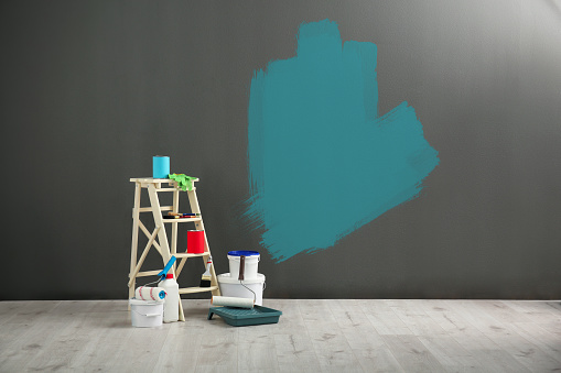 Set with decorator's tools and paint on floor near grey wall