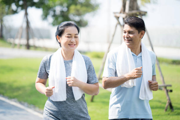 夏のスポーツランニング衣装で幸せな成熟したカップル。屋外で走る�アジア人の男女。 - senior couple ストックフォトと画像