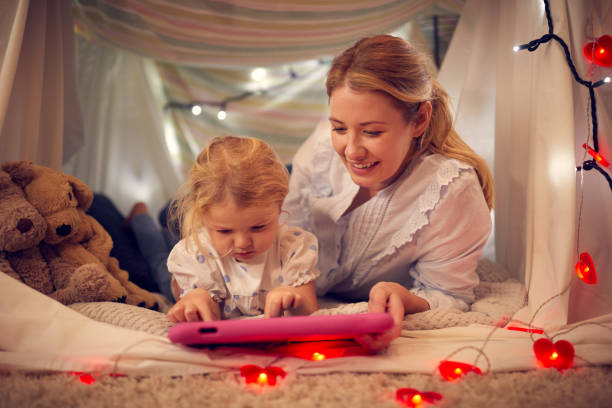 집에서 아이의 침실에서 집에서 만든 캠프에서 디지털 태블릿을보고 어머니와 어린 딸 - ipad 2 뉴스 사진 이미지