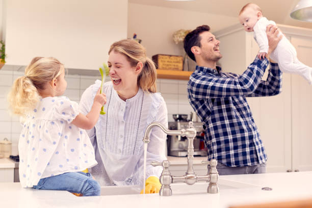 istock Smiling Family Having Fun In Kitchen Doing Washing Up At Sink Together 1319228749