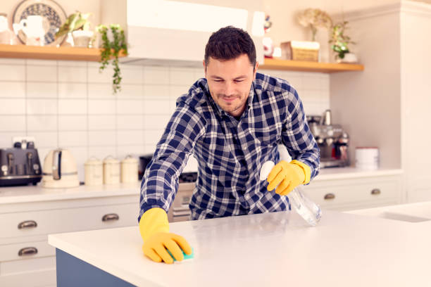 istock Man At Home In Kitchen Doing Housework And Cleaning Counter Surface With Spray 1319229112