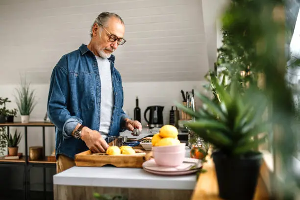 Senior man at home, preparing morning tea in domestic kitchen.