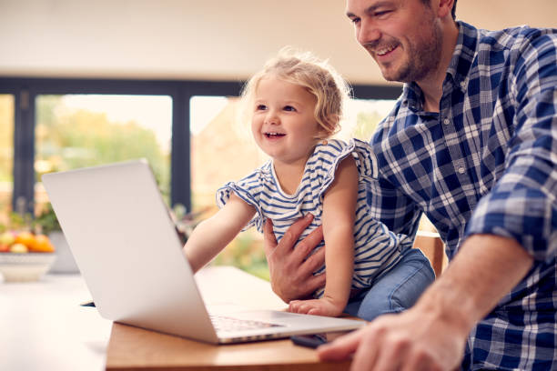istock Working Father Using Laptop At Home On Kitchen Counter Whilst Looking After Young Daughter 1319230554