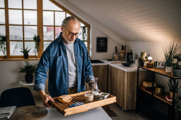istock Senior man serving cup of tea on a tray in the kitchen 1319230693