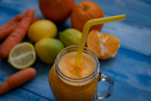 Tasty carrot juice on blue wooden table outdoors