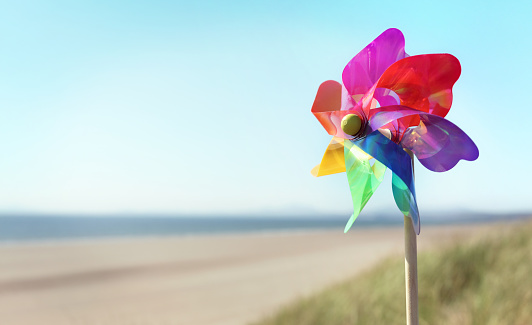 Summer beach background, pinwheel or windmill in the sand concept for vacation copy or message