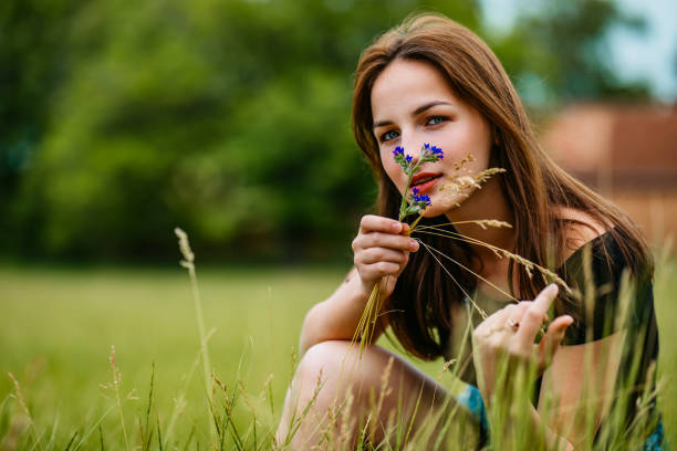 Portrait of pretty young Caucasian woman crouching in grass.
