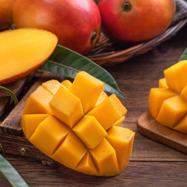 istock Mango. Fresh mango fruit with leaves over dark wooden table background. 1319233318