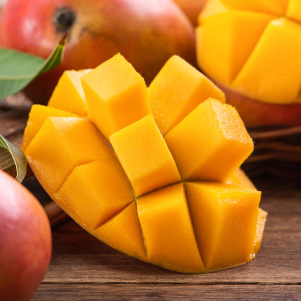 istock Mango. Fresh mango fruit with leaves over dark wooden table background. 1319233442