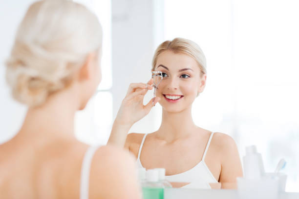 istock woman with curler curling eyelashes at bathroom 1319234400