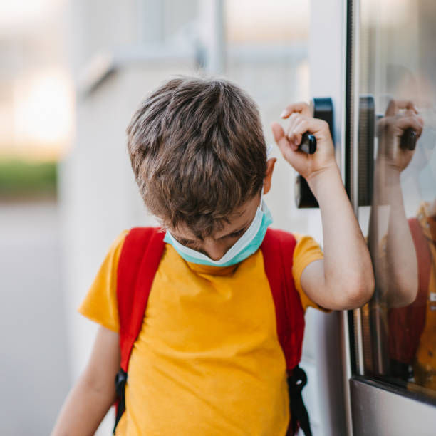 istock Schoolboy with the mask on opening school door 1319234831