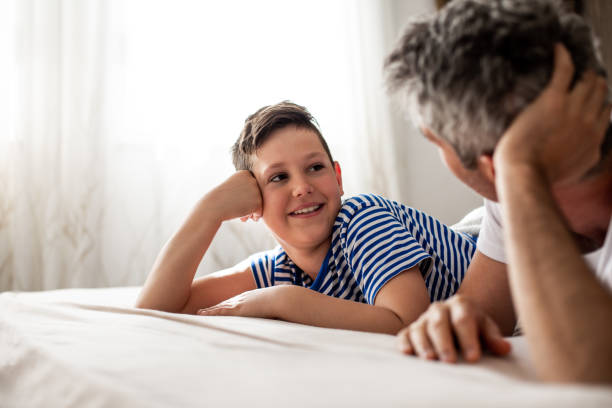 istock Father and son lying on bed, talking and smiling. 1319234930