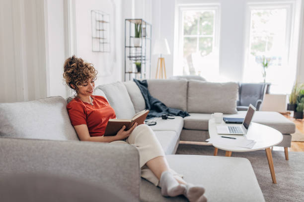 istock Woman reading a book on sofa 1319240191