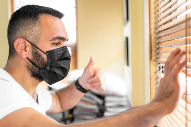istock Handsome looking from window to quarantine with mask 1319241146