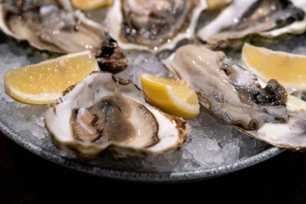 istock Fresh oysters in shells in plate with crushed ice and lemon slices 1319245015