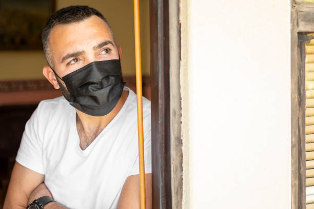 istock Handsome looking from door to quarantine with mask 1319252354