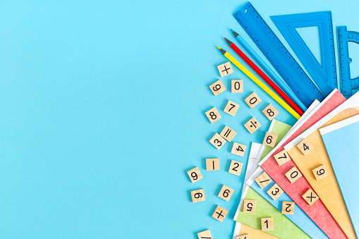 Bright multicolored school supplies, stationery on a blue background. A group of school subjects. Back to school, early childhood education. Study of mathematics and other sciences. Flat lay.