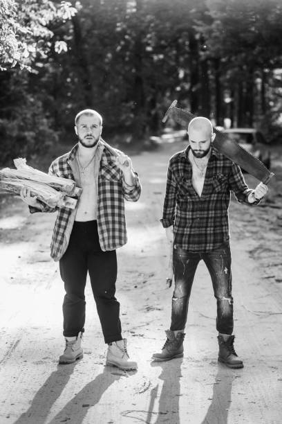 istock Two bearded brutal woodcutters with hand saw and axe 1319254269