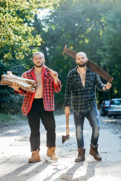 istock Two bearded brutal woodcutters with hand saw and axe 1319254485