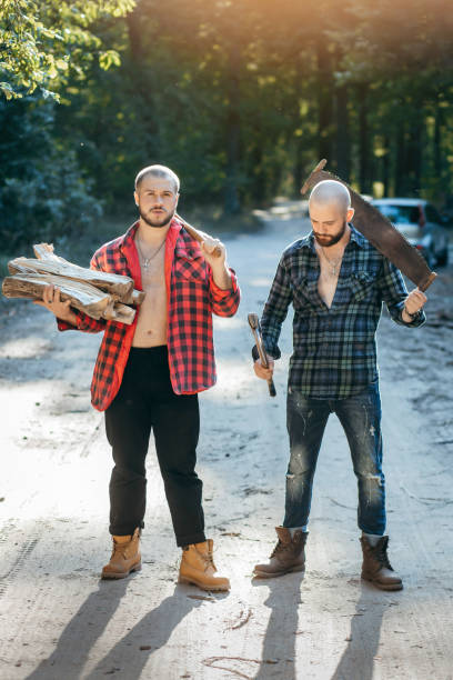 istock Two bearded brutal woodcutters with hand saw and axe 1319254532