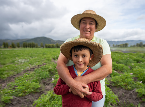 Portrait of a Latin American mother and son farming their land  and looking at the camera smiling - agricultural lifestyle concepts