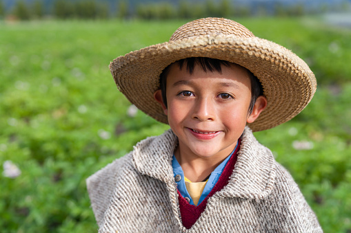 Portrait of a Happy Latin American boy helping with the harvest at a farm and looking at the camera smiling