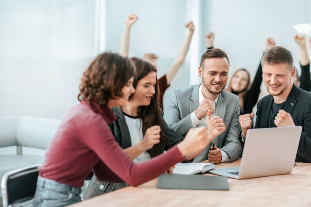 istock happy team of employees looking at laptop screen 1319257915