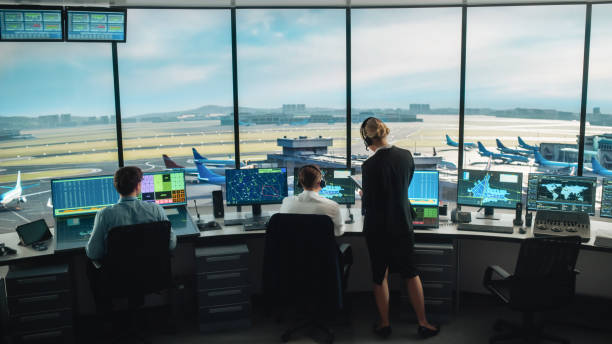 Diverse Air Traffic Control Team Working in a Modern Airport Tower. Office Room is Full of Desktop Computer Displays with Navigation Screens, Airplane Departure and Arrival Data for Controllers. equipo diverso de control de tráfico aéreo trabajando en una torre moderna del aeropuerto. la sala de oficina está llena de pantallas de computadoras de escritorio con pantallas de navegación, datos de salida y llegada de aviones para los controladores