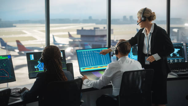 female and male air traffic controllers with headsets talk in airport tower. office room is full of desktop computer displays with navigation screens, airplane departure and arrival data for the team. - color image people air vehicle airplane imagens e fotografias de stock