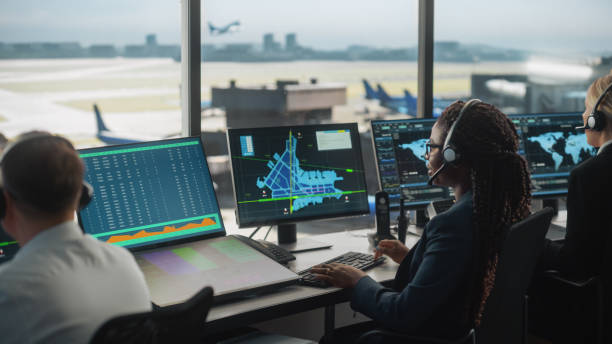 空港タワーの通話でヘッドセットを持つ女性の航空管制官が話します。オフィスルームは、ナビゲーション画面、チームのための飛行機のフライトレーダーデータとデスクトップコンピュー� - air traffic control tower ストックフォトと画像
