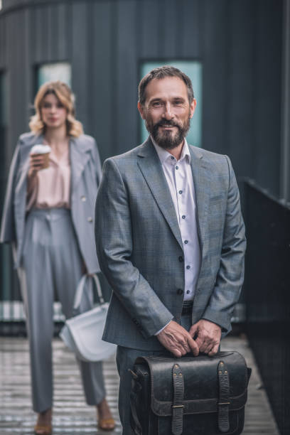 istock Smiling man with briefcase and woman with coffee behind 1319259746