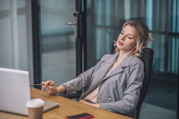 istock Woman looking at laptop leaning back in chair 1319259815