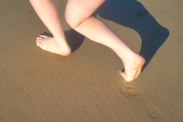 istock Female feet walking away on sand 1319262802