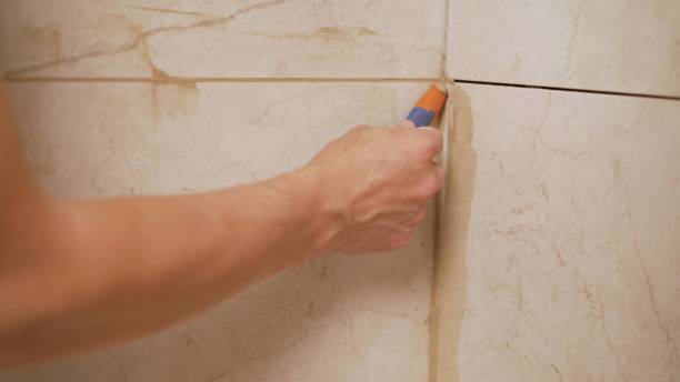 istock The master is rubbing the seam between the tiles. master tiler glues wall white ceramic tiles. master tiler glues wall white ceramic tiles. 1319265539