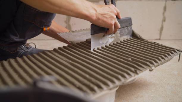 The master smears the tiles with glue. The master tile smears the mucilage solution on the marble tile. stock photo