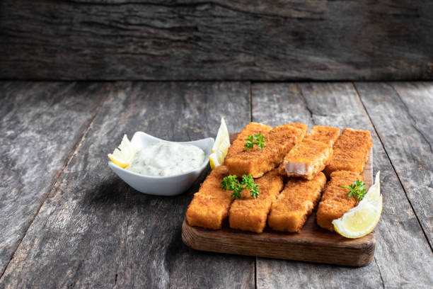 Fried fish fingers with lemon and sauce tartare on wooden table Fried  fish fingers with lemon and sauce tartare on wooden table fish stick stock pictures, royalty-free photos & images