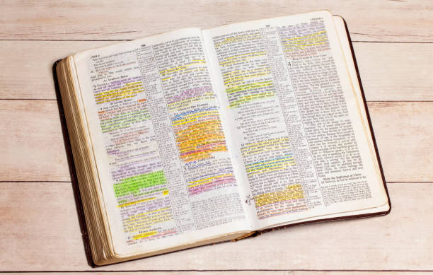 a used and highlighted bible open on a white wood table - bible imagens e fotografias de stock