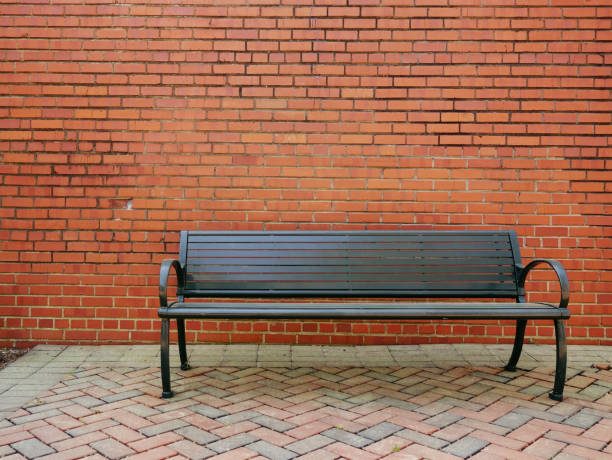 istock An empty park bench in front of a blank brick wall 1319271810