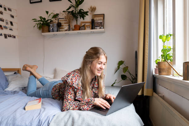 молодая женщина, лежащая на кровати - college dorm стоковые фото и изображения