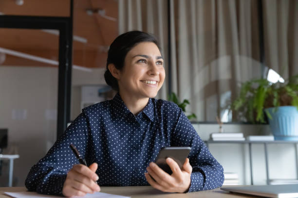 istock Happy Indian woman work with smartphone making plans 1319284395