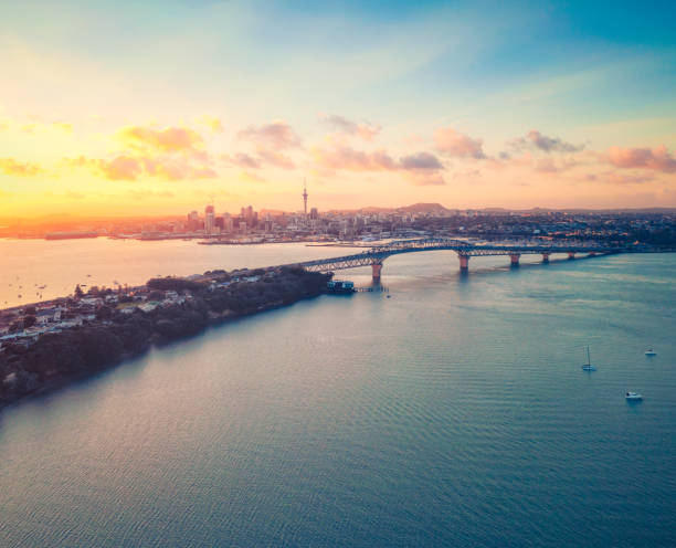 Auckland Sunrise A high angle view of Auckland's sunrise, with the cityscape and Harbour Bridge seen across Waitemata Harbour. auckland stock pictures, royalty-free photos & images