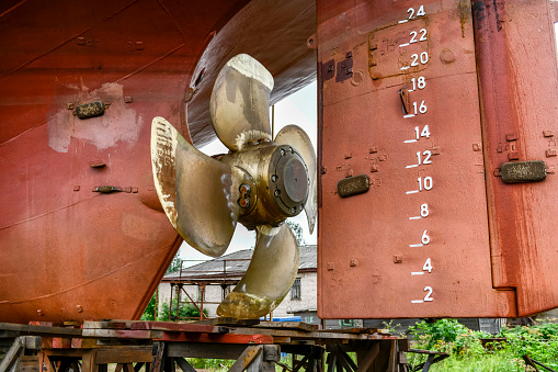 Variable pitch propeller and rudder. Cargo vessel ashore on ship repairing yard.