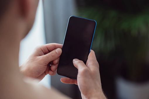 Unrecognizable man tracking his progress on smartphone app after home workout training