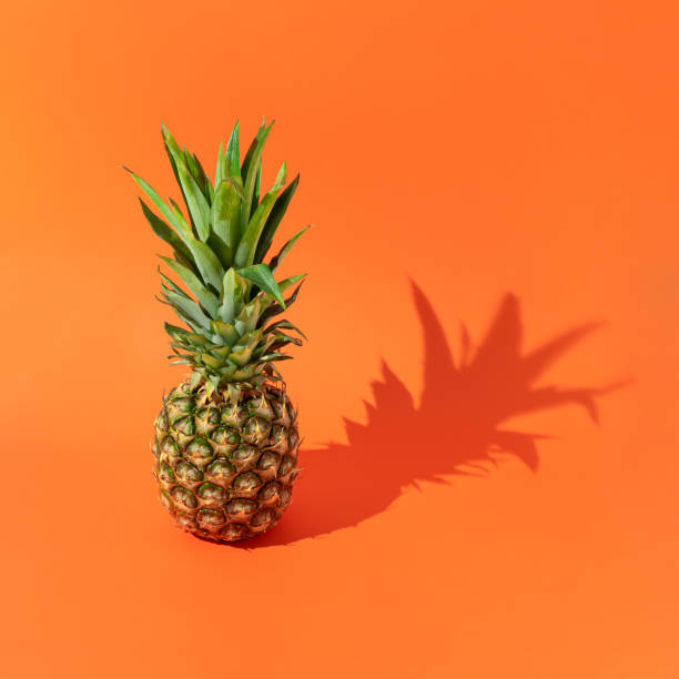 istock Pineapple fruit with sunny day shadow against a bold orange background. Minimal summer food concept.  Copy space. 1319289046