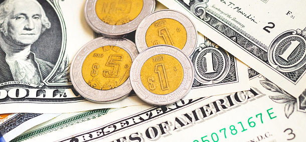 Money, Mexican Peso and US Dollar. Mexico money coins over American dollar bills. Foreign exchange market, economy, international travel concept.