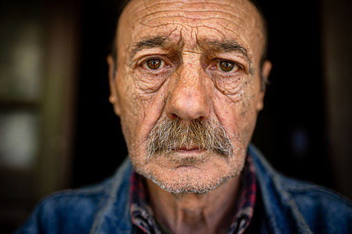 A close-up of an older man with a calm look in his eyes. Loneliness and depression