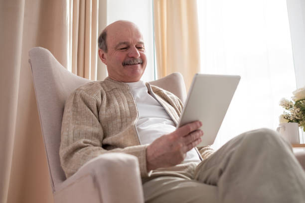 istock Senior man in sofa with tablet computer at home 1319293244